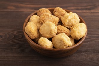 Fried crispy Chicken Nuggets on brown wooden background. side view, close up