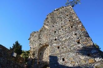 An ancient stone tower rises against a bright blue sky as an ancient structure, Mystras, Mistra,