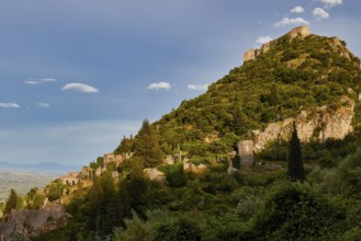 Byzantine Castle of Mystras, Ancient ruins spread on a green hill under a clear blue sky, Mystras,
