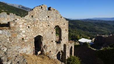 Ruins on a hill overlooking a vast mountain landscape under a clear blue sky, Mystras, Mistra,
