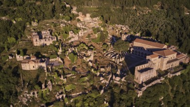 Aerial view of a large part of the Byzantine city of Mystras, surrounded by forest and mountains,