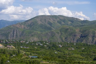 Wide valley with green hills and a few scattered houses under a blue sky, view of Garni, Kotayk