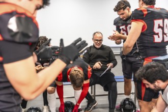 American football coach smiling, discussing strategy, and preparing for a game with diverse male