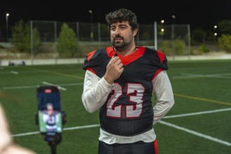 American football player wearing a jersey with number 23 giving an interview on a sports field at