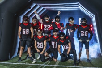 American football team players standing ready to enter the stadium through a tunnel, wearing