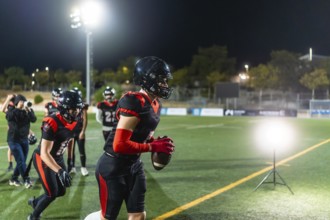 Female american football player training on a stadium field at night, wearing a helmet and uniform,