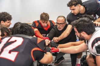 American football coach and players huddling in a locker room, getting motivated for a game while