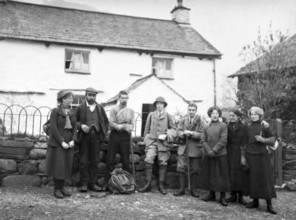 Men and women in mountaineering mountain climbing group standing in fron of cottage, c 1900-1920
