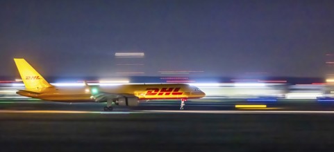 Stuttgart Airport in the early morning. DHL cargo plane landing. Light traces with motion blur.