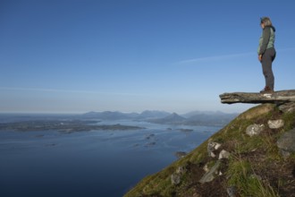 Woman with walking sticks standing on a ledge, Rørsethornet stone stairs, with 3292 steps one of