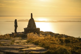 Woman standing next to cairn and looking at the sea, Rørsethornet stone staircase, with 3292 steps
