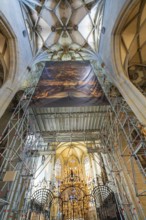 Magnificent church interior with scaffolding and golden decorations, covered by a painted banner,