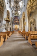 Gothic church with detailed construction, wooden benches and large painted banner above the altar