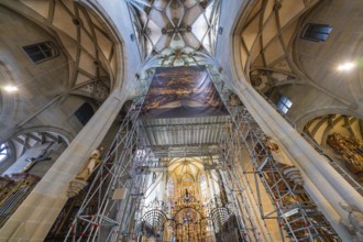 Church ceiling with elaborate scaffolding and artistic details, play of light emphasises the