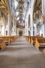 Impressive nave with organ and symmetrically arranged wooden benches under a vaulted ceiling, St