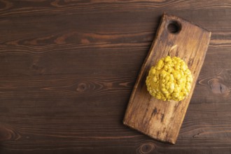 Decorative orange Pumpkin with tumors on cutting board on brown wooden background, top view, flat