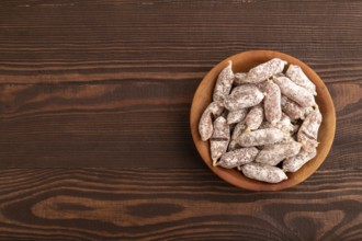 Small smoked Chicken sausages in wooden bowl on brown wooden background. top view, flat lay, copy