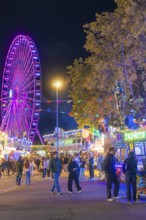 Festive atmosphere with fairy lights and a large Ferris wheel at night, Cannstatter Wasen folk