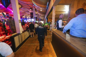 Security guard in a well-filled marquee with atmospheric lighting, Cannstatter Wasen folk festival,