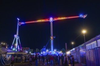 Lively funfair at night with colourful lights and many visitors, Cannstatter Wasen funfair,