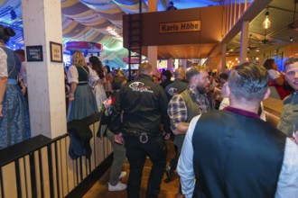 Lively beer tent with security guards and festive atmosphere, Cannstatter Wasen folk festival,