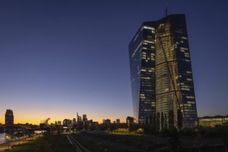 The lights of the European Central Bank (ECB) and the Frankfurt banking skyline glow in the