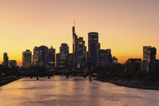 The evening sky behind the Frankfurt banking skyline glows orange and yellow shortly after sunset,