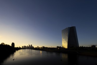 The light of the setting sun is reflected in the glass façade of the Frankfurt banking skyline,