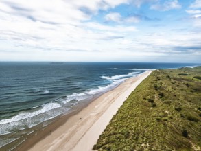 Beach and Dunes over Bamburgh Castle from a drone, Northumberland, Northeast Coast, England, United
