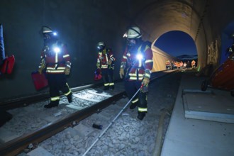 Firefighters walk along tracks in a tunnel at night, firefighting exercise in the new tunnel of the