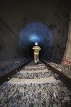Single firefighter in illuminated tunnel on rails, firefighting exercise in the new tunnel of the