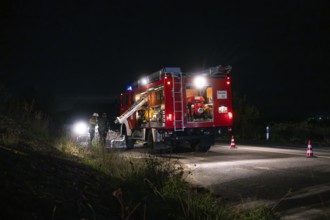 Fire engine with bright lights standing on a road at night, surrounded by traffic cones, fire
