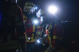Group of firefighters with breathing masks and lights during a night operation, firefighting