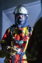 Firefighter with breathing mask and protective clothing in a building, firefighting exercise in the
