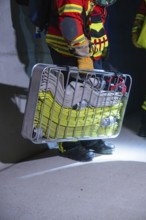 Firefighter holding hose carrier basket in illuminated area, ready for action, firefighting