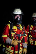 Firefighter with breathing apparatus in the dark, concentrated and ready for action, firefighting