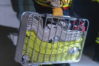 Firefighter carrying hose basket with folded hoses, ready for action, firefighting exercise in the