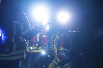 Firefighters illuminated with glare lights, in protective suits, on duty at night, firefighting