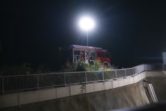 Fire engine under a street lamp next to a fence and plants at night, fire drill in the new