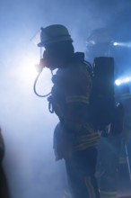 Firefighters with breathing masks in a foggy environment with bright light, firefighting exercise