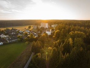 Landscape at sunset with a village and surrounding forests in warm light, fire drill in the new