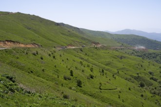 Road runs along the green hills in a landscape with mountains, at the highest pass in Armenia,