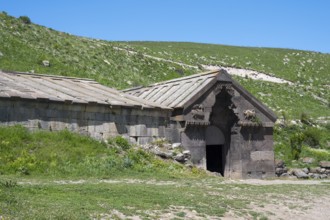 Stone building in a rural setting with a green hill in the background, Orbelian's Caravanserai,