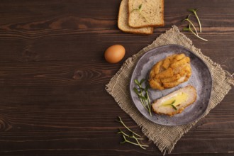 Chicken Schnitzel on gray plate with microgreen on brown wooden background and linen textile. top