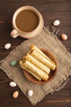 Waffles with caramel on brown wooden background and linen textile, cup of coffee, top view, flat
