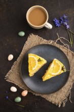 Lemon cake on black concrete background and linen textile, cup of coffee, top view, flat lay, close