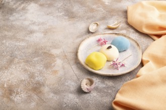 Japanese Mochi Cakes on brown concrete background and orange textile, side view, copy space