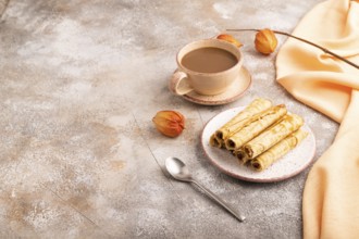 Waffles with caramel on brown concrete background and orange linen textile, cup of coffee, side