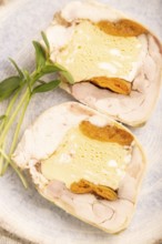 Chicken, egg and dried apricot meatloaf, microgreen on brown concrete background and linen textile.