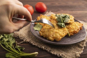 Fried crispy Chicken pancakes with hand on brown wooden background and linen textile. side view,